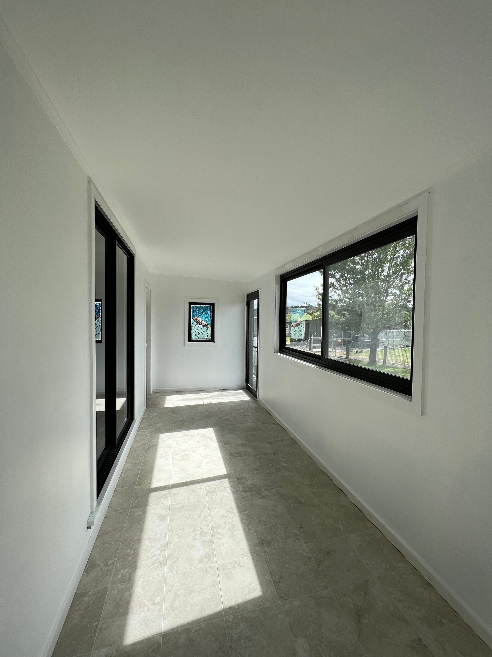 A long hallway with a lot of windows and a picture on the wall — JWM Allround Carpentry Construction in Goulburn, NSW