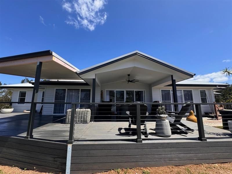 A Grey-painted House With a Large Wooden Deck on a Sunny Day — J&C Quality Construction in Goulburn, NSW