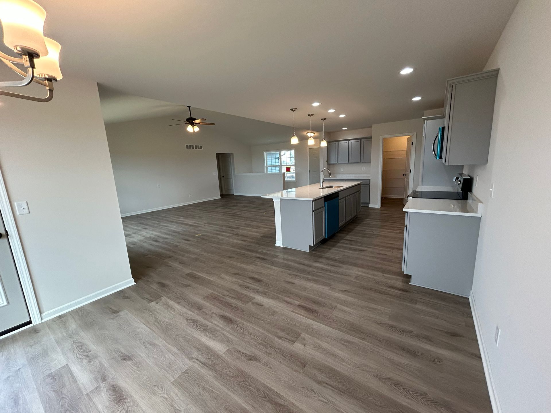 Open-concept living space with gray kitchen cabinets, island, and light wood flooring.