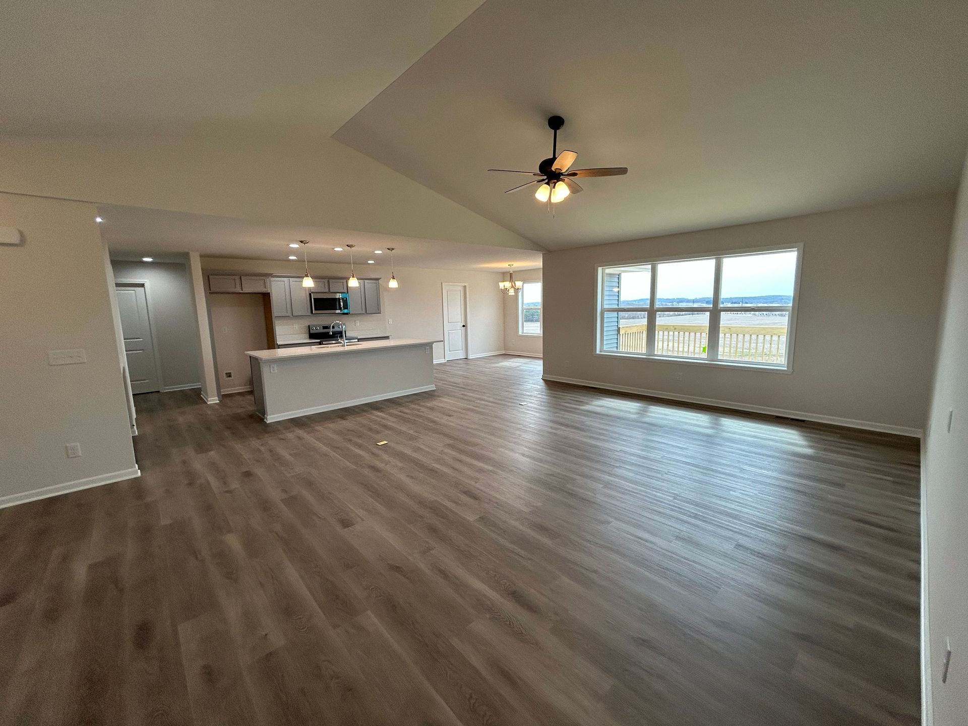 Open-concept living area: kitchen with island, living room with windows, and wooden floors.