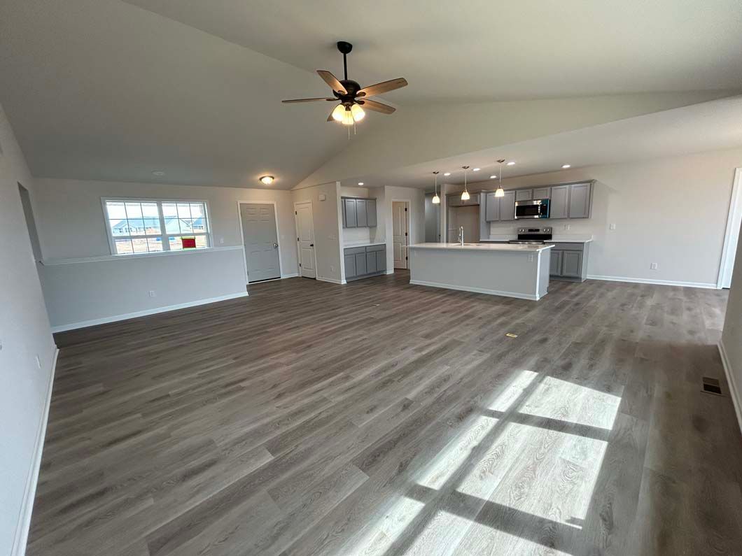 Open-concept living space with light wood floors, vaulted ceiling, and gray kitchen.