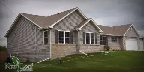 Gray house with a brown roof and green lawn.