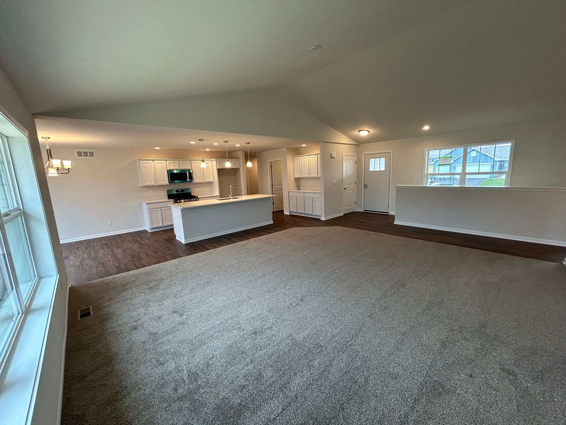 Open-concept living area with a kitchen, white cabinets, and dark floors.