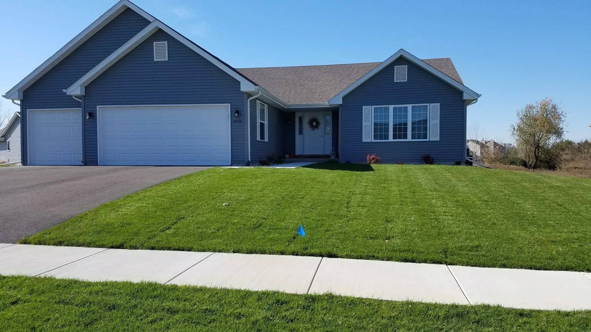 Blue house with white trim, green lawn, and a driveway.