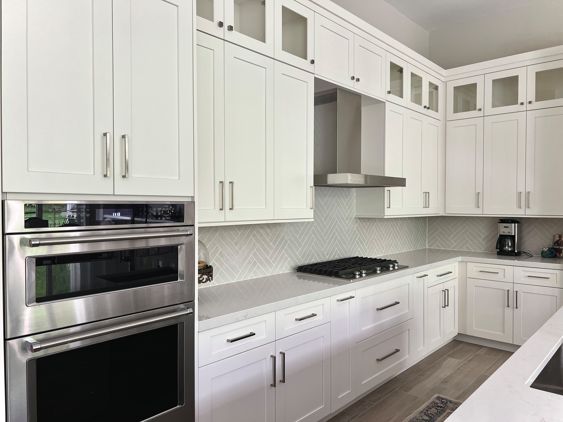 White kitchen cabinets and appliances. Stainless steel oven and range hood.