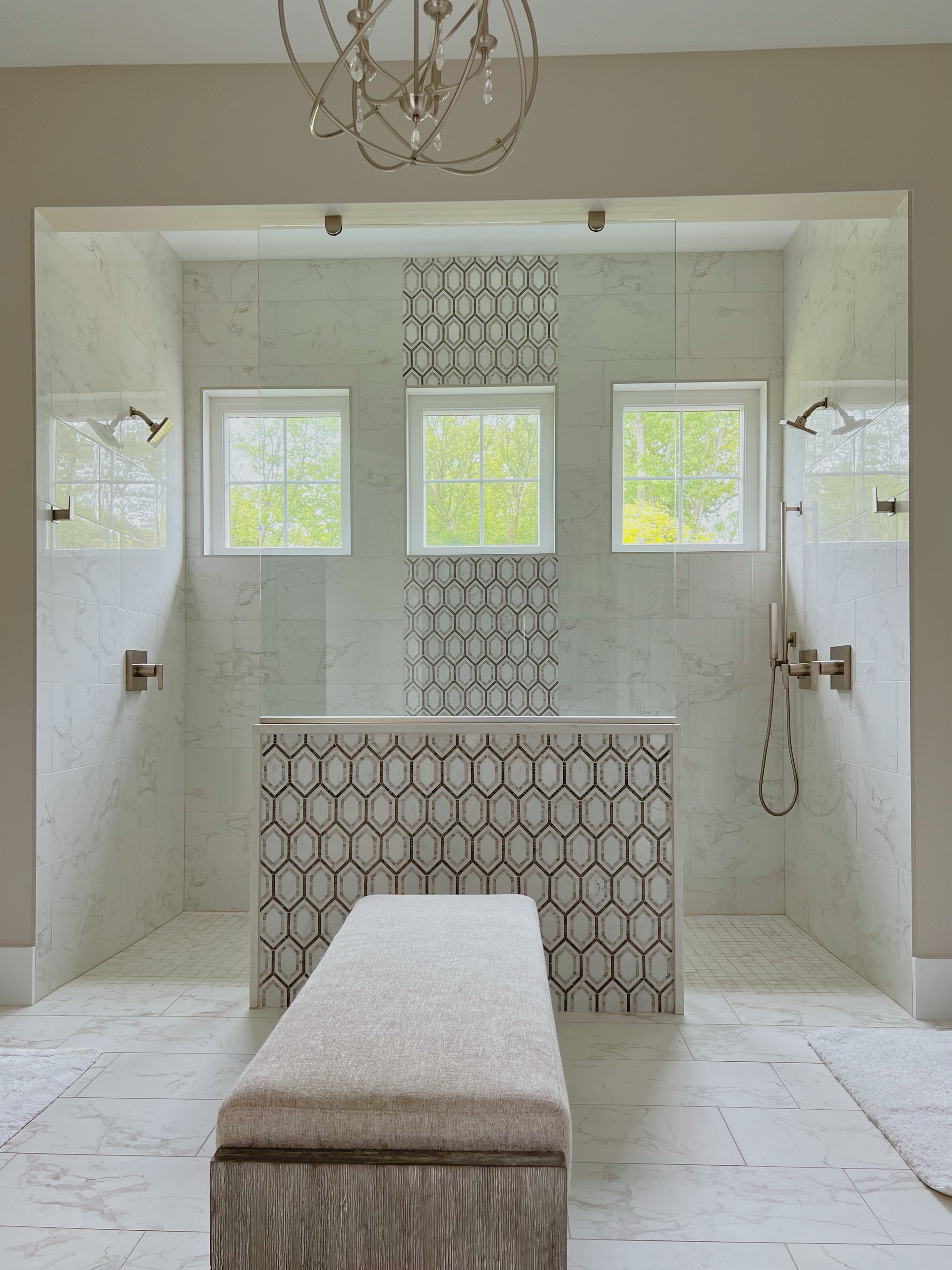 Luxury bathroom with white tile, a mosaic feature wall, a shower bench, and a chandelier.