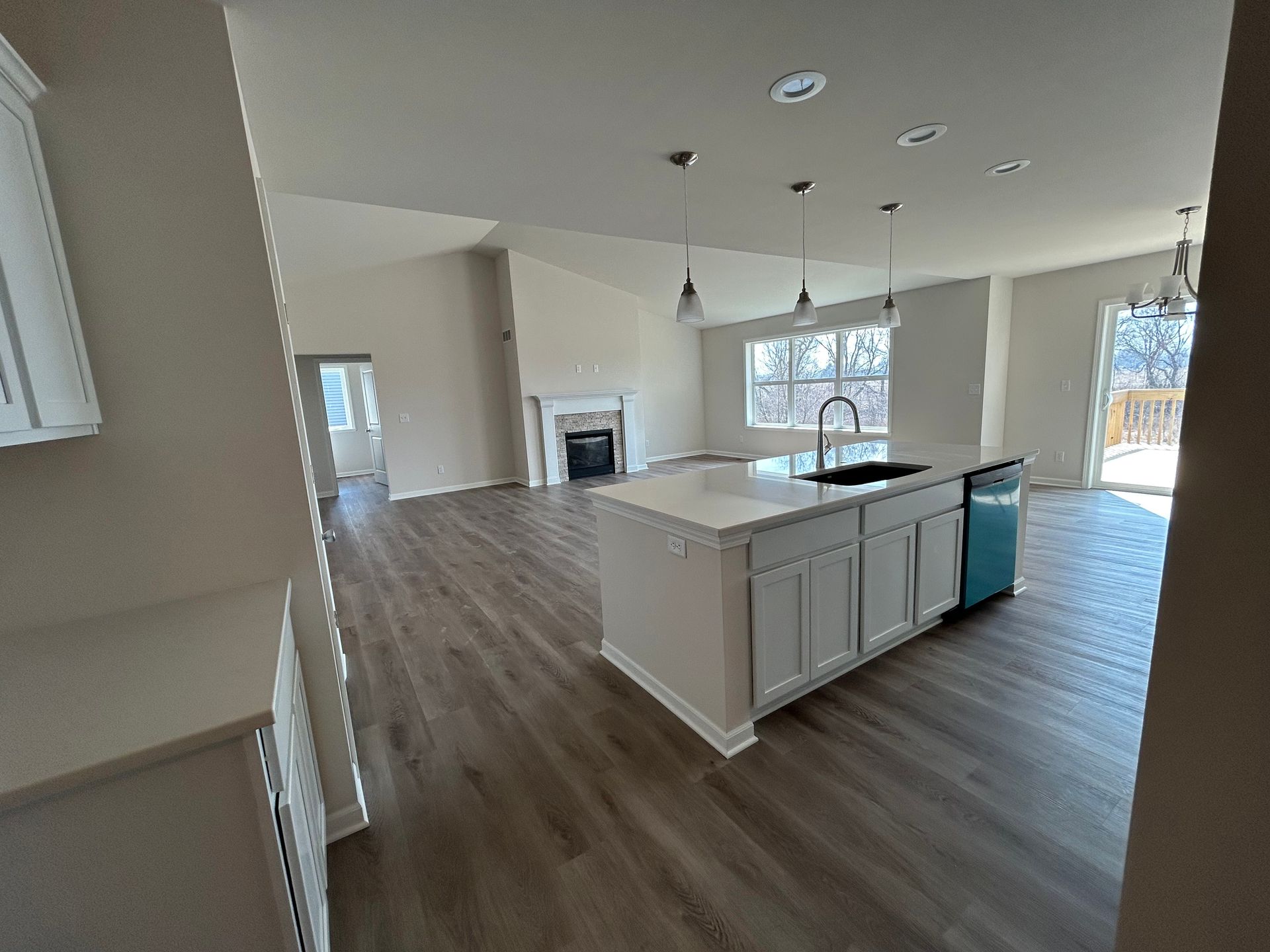 Open-concept kitchen with island, light wood floors, white cabinets, and a fireplace.