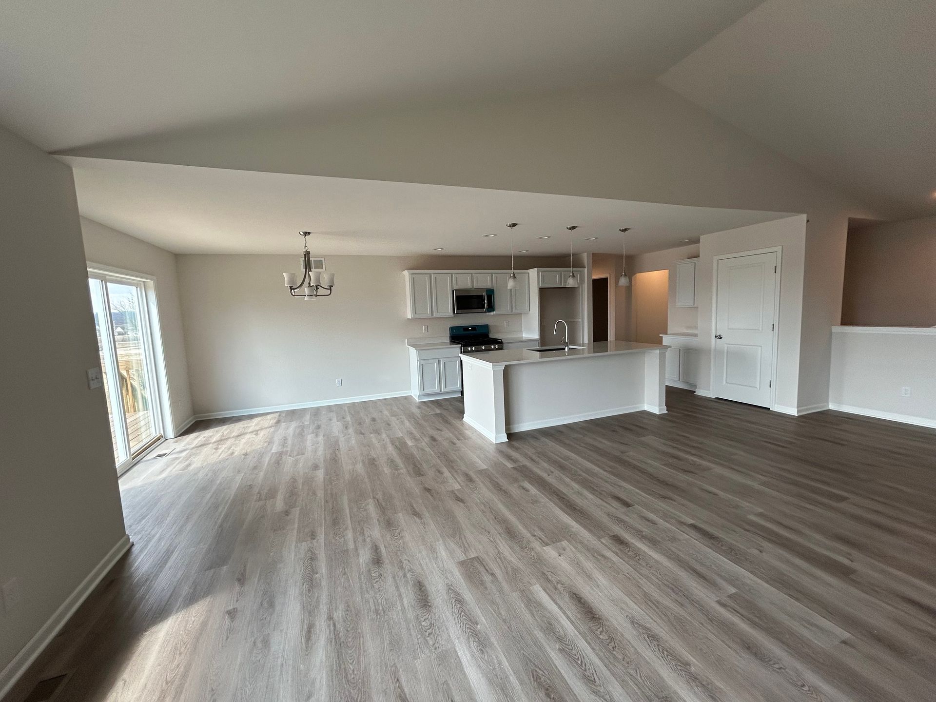 Open-concept kitchen and living area with white cabinets, island, and light wood floors.