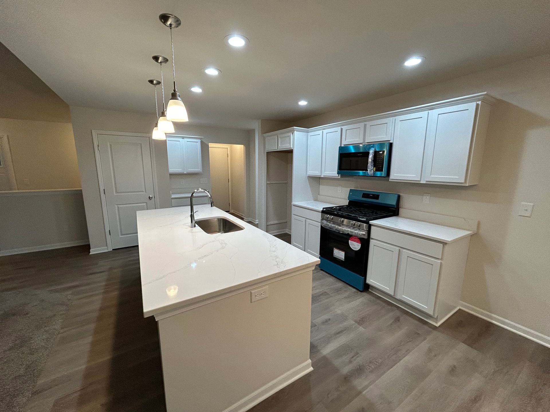 Modern kitchen with white cabinets, island, and stainless steel appliances.