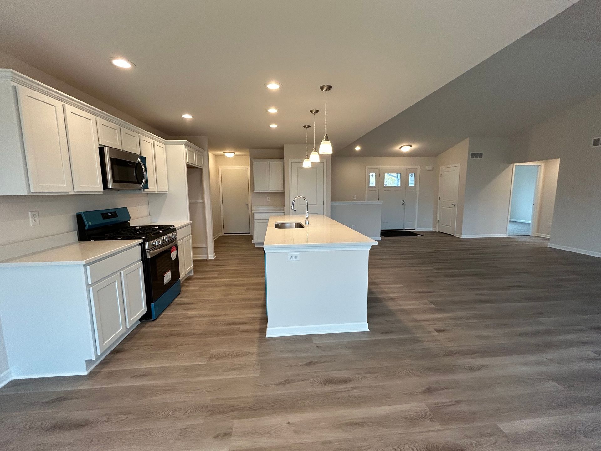 White kitchen with island, stainless appliances, and grey floors.