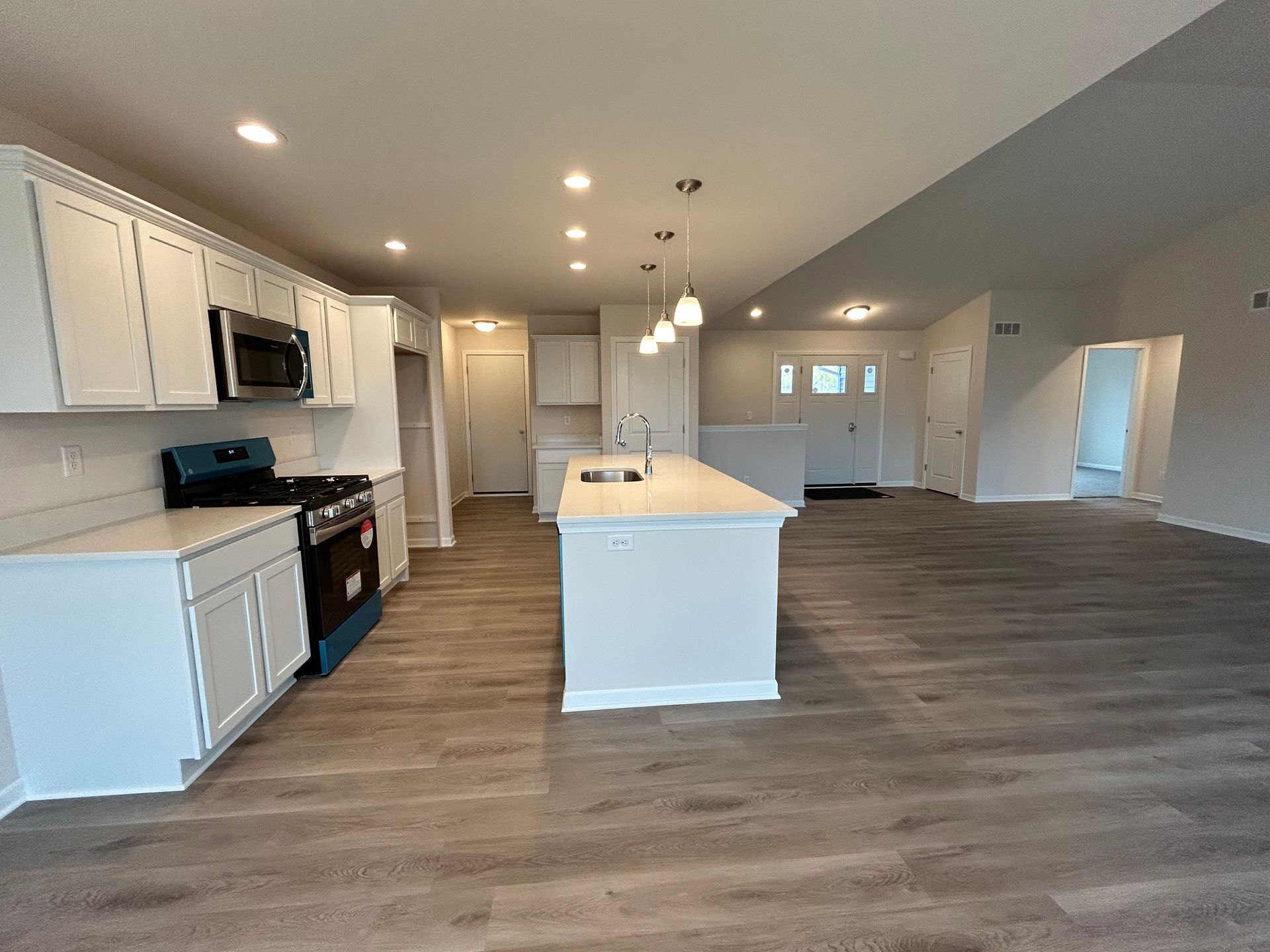 Bright, modern kitchen with white cabinets, island, and stainless steel appliances. Gray flooring.