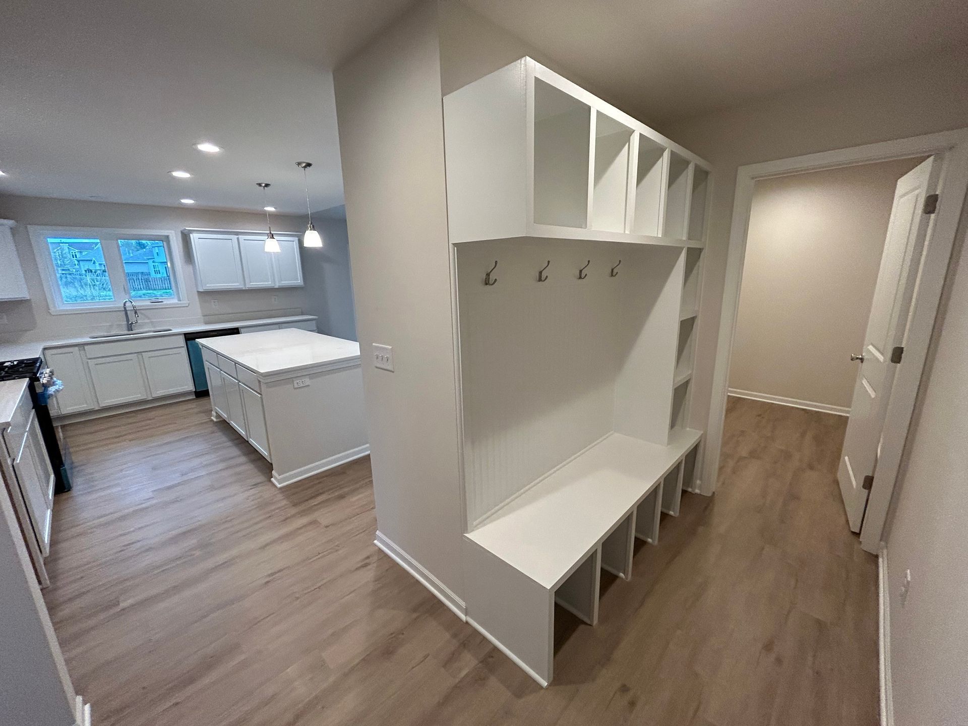 A modern entryway with a built-in storage bench and open kitchen.