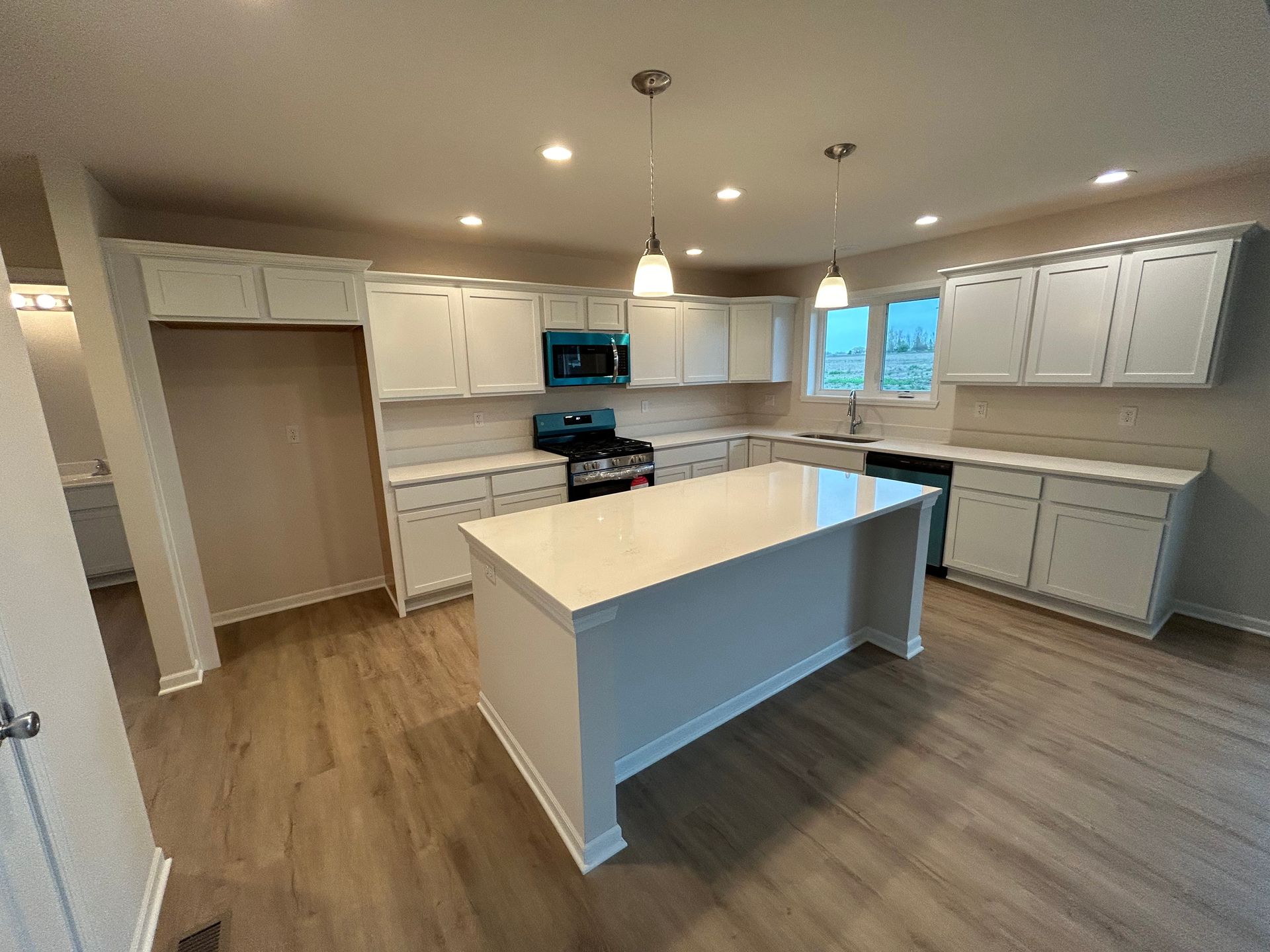 Modern white kitchen with island and blue oven.
