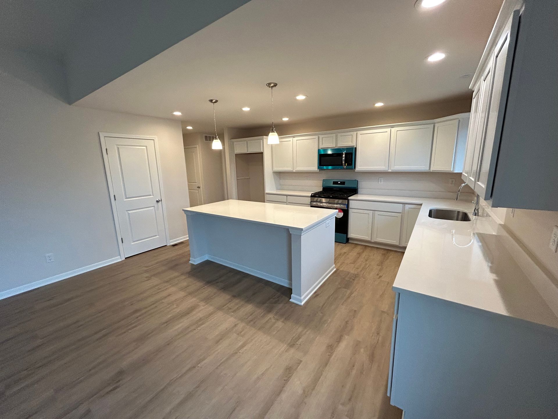 White kitchen with island and cabinets; light wood floors.