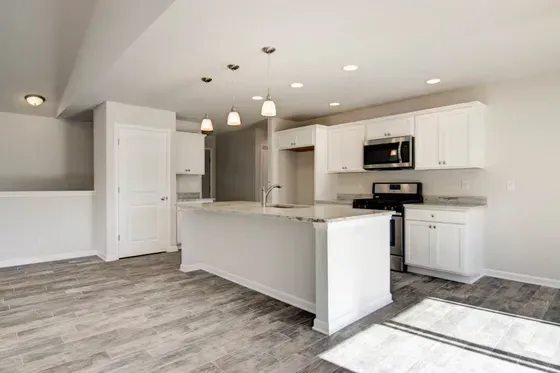 White kitchen with island, cabinets, appliances, and gray wood-look flooring.