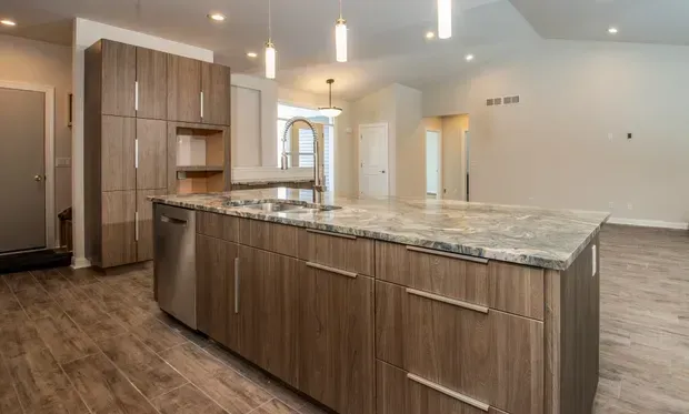 Modern kitchen with wood cabinets, stainless steel appliances, granite island, and light wood flooring.