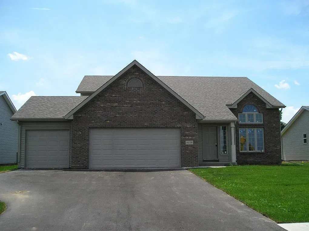 Brick house with attached two-car garage and arched window, front yard, and driveway.