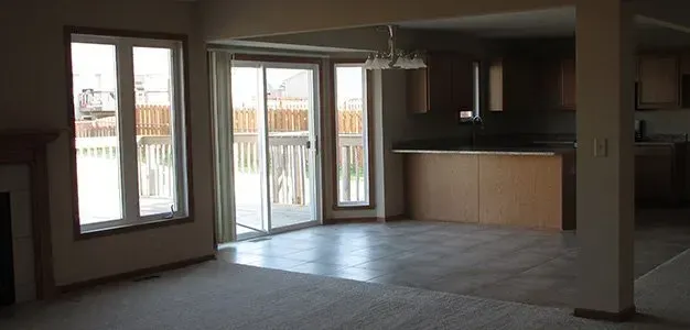 Interior view of an empty living room with a view of a deck through a sliding glass door.