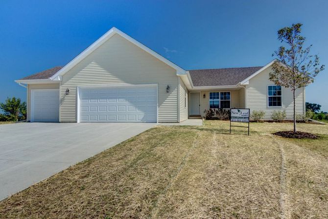 Beige ranch home with a two-car garage on a sunny day.
