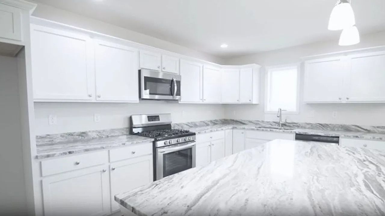 White kitchen with granite countertops, stainless steel appliances, and island.