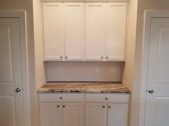White cabinets with a countertop and two doors.