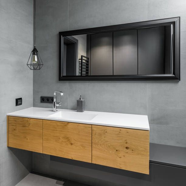 A bathroom with a sink , mirror and wooden cabinets