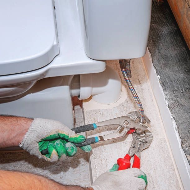 A man is fixing a toilet with pliers.