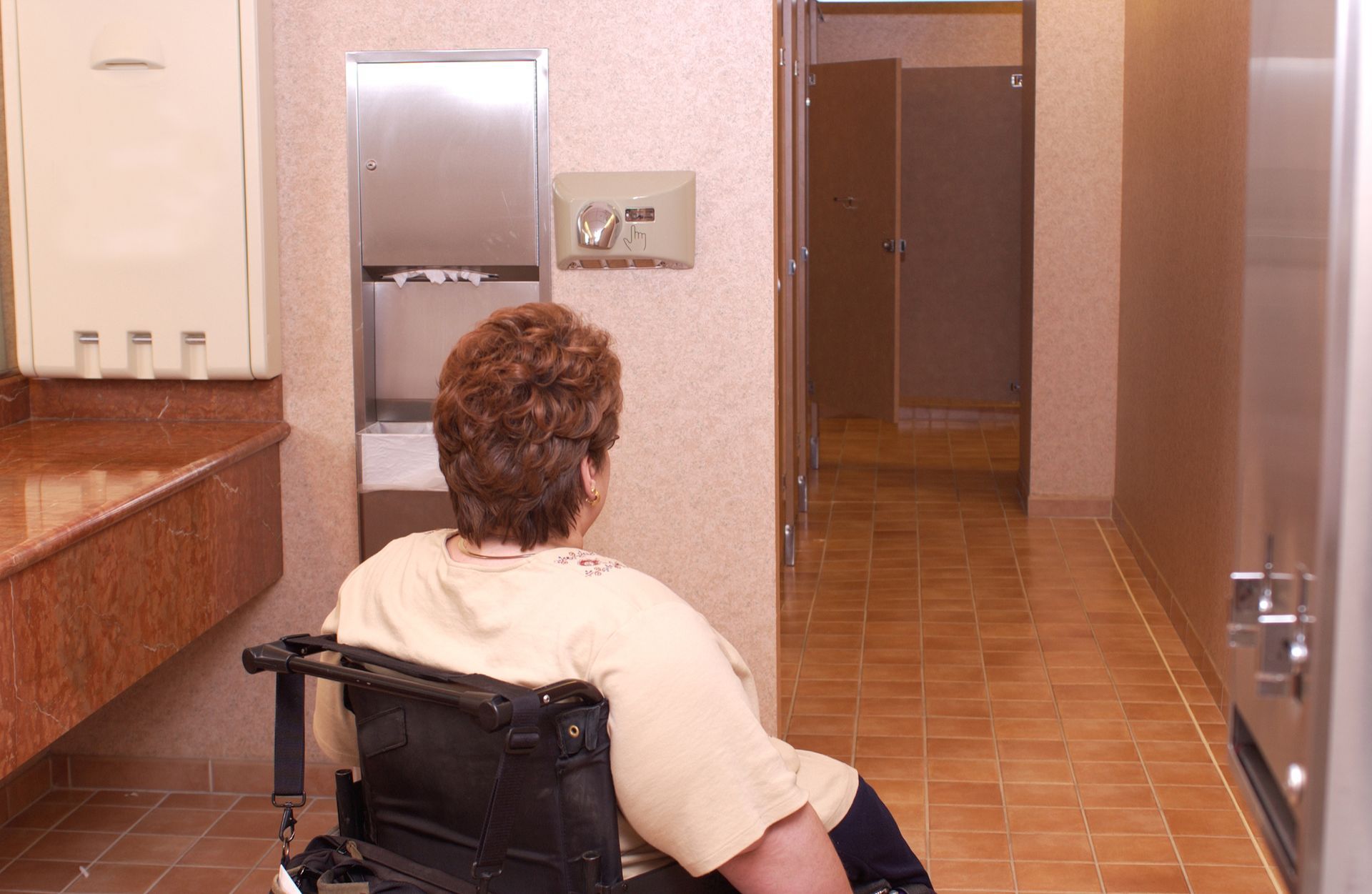 A woman in a wheelchair is sitting in a bathroom