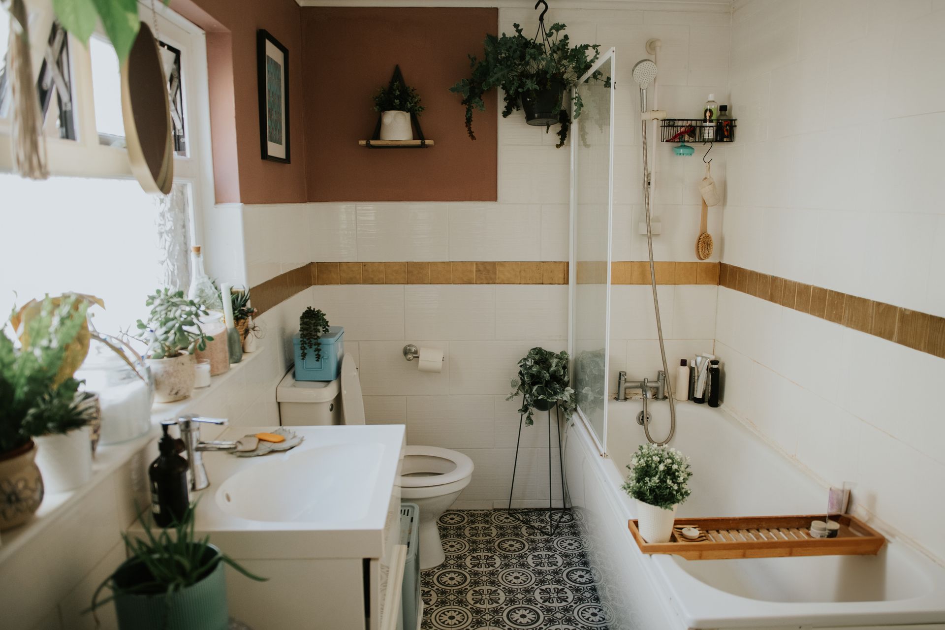 A bathroom with a sink , toilet , bathtub and plants.