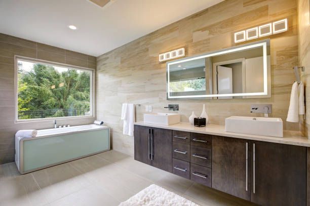 A bathroom with two sinks , a tub , and a large mirror.
