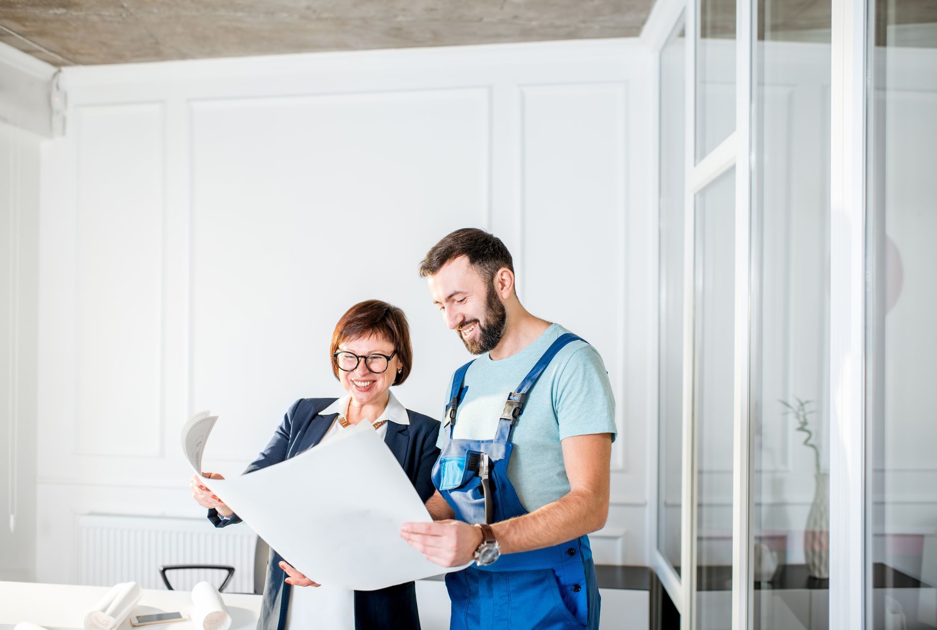 A man and a woman are looking at a blueprint together.