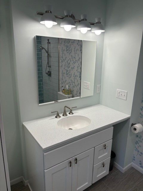 A bathroom with a sink , mirror and light fixtures