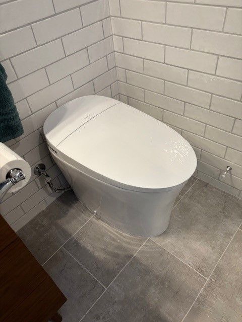 A white toilet is sitting in a corner of a bathroom.