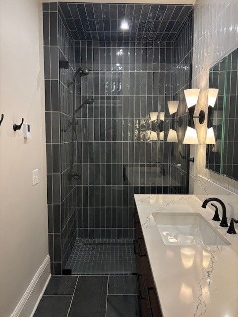 A bathroom with a walk in shower , sink and mirror.