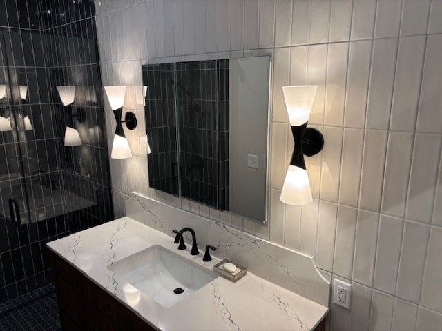 A bathroom with a sink , mirror , and lights.