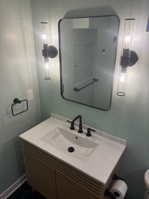 A bathroom with a sink , mirror and toilet.