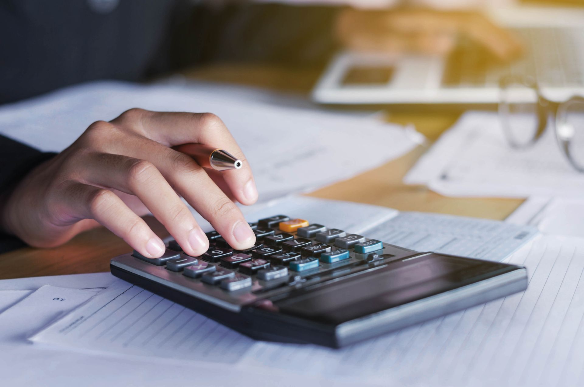 A person is using a calculator while holding a pen.