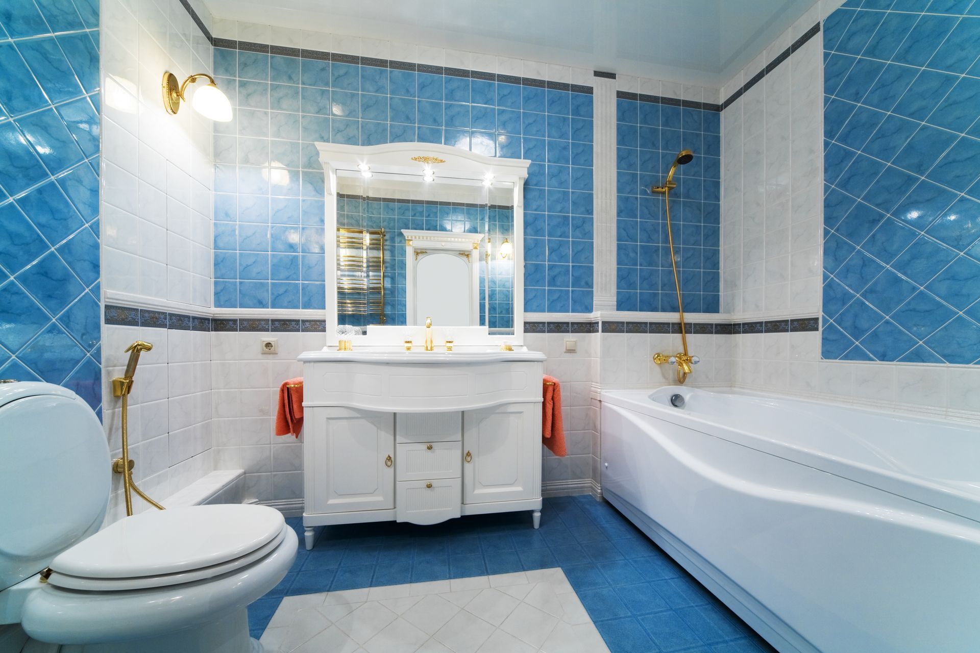 A bathroom with blue and white tiles , a toilet , sink and bathtub.