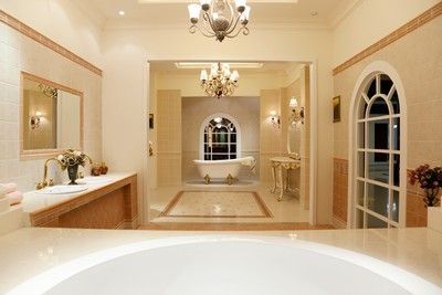 A bathroom with a tub , sink , mirror and chandelier
