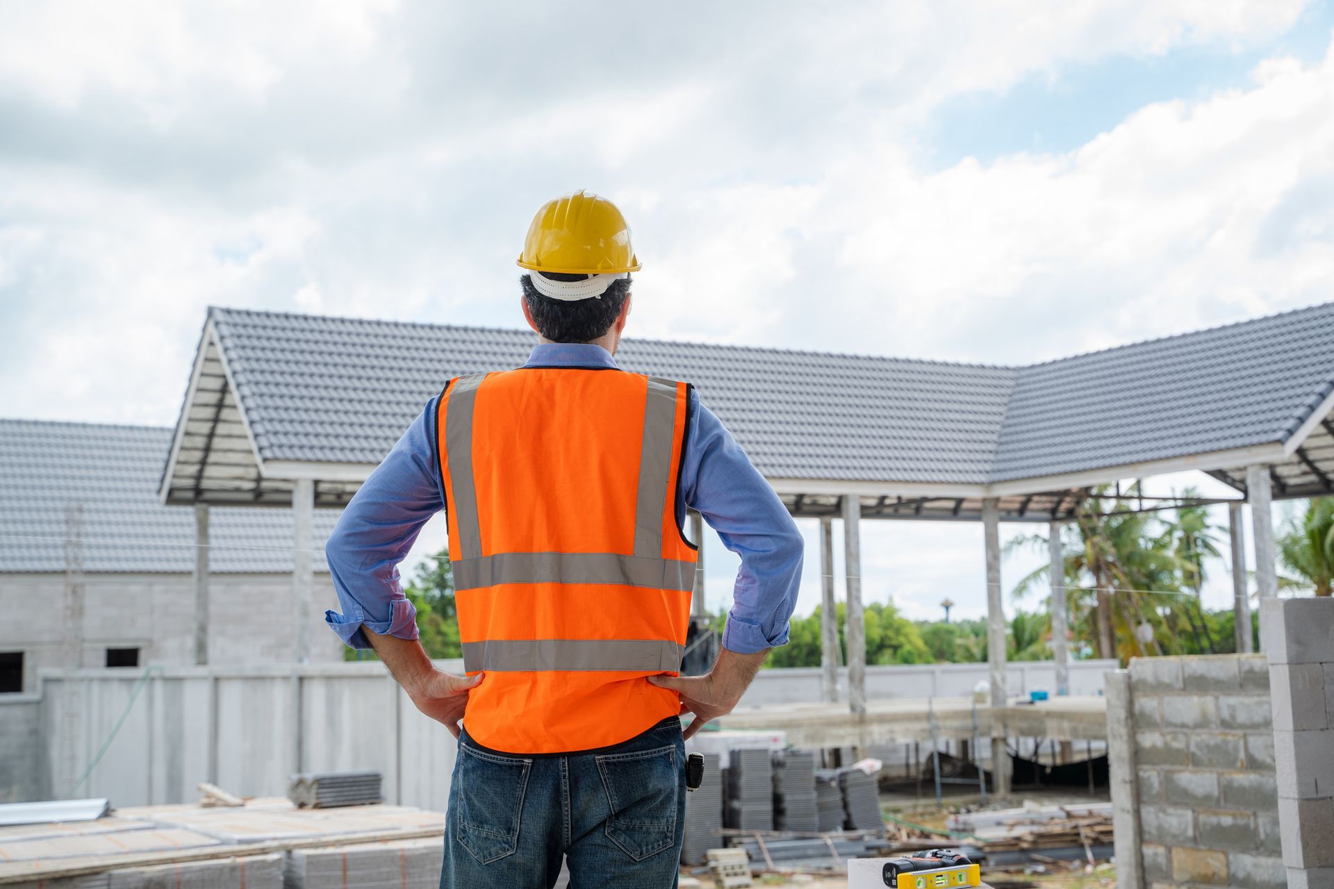 A construction worker is standing in front of a building under construction.