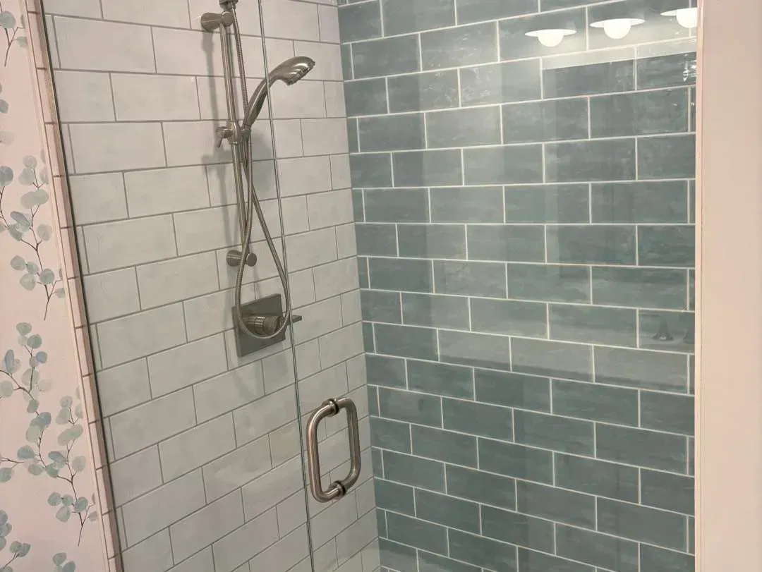 A shower with blue tiles and a glass door