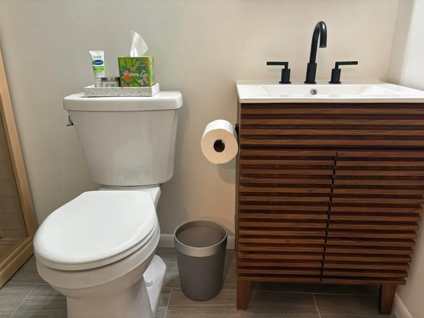 A bathroom with a toilet , sink and trash can.