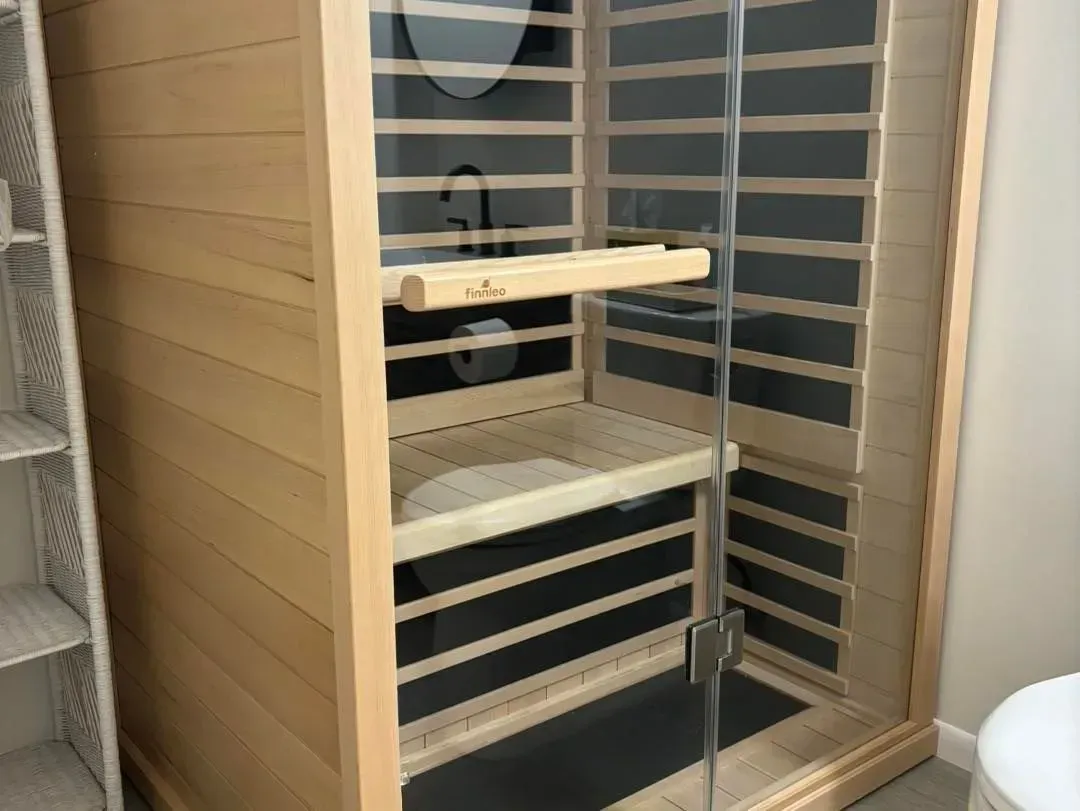 A sauna is sitting in a bathroom next to a toilet.