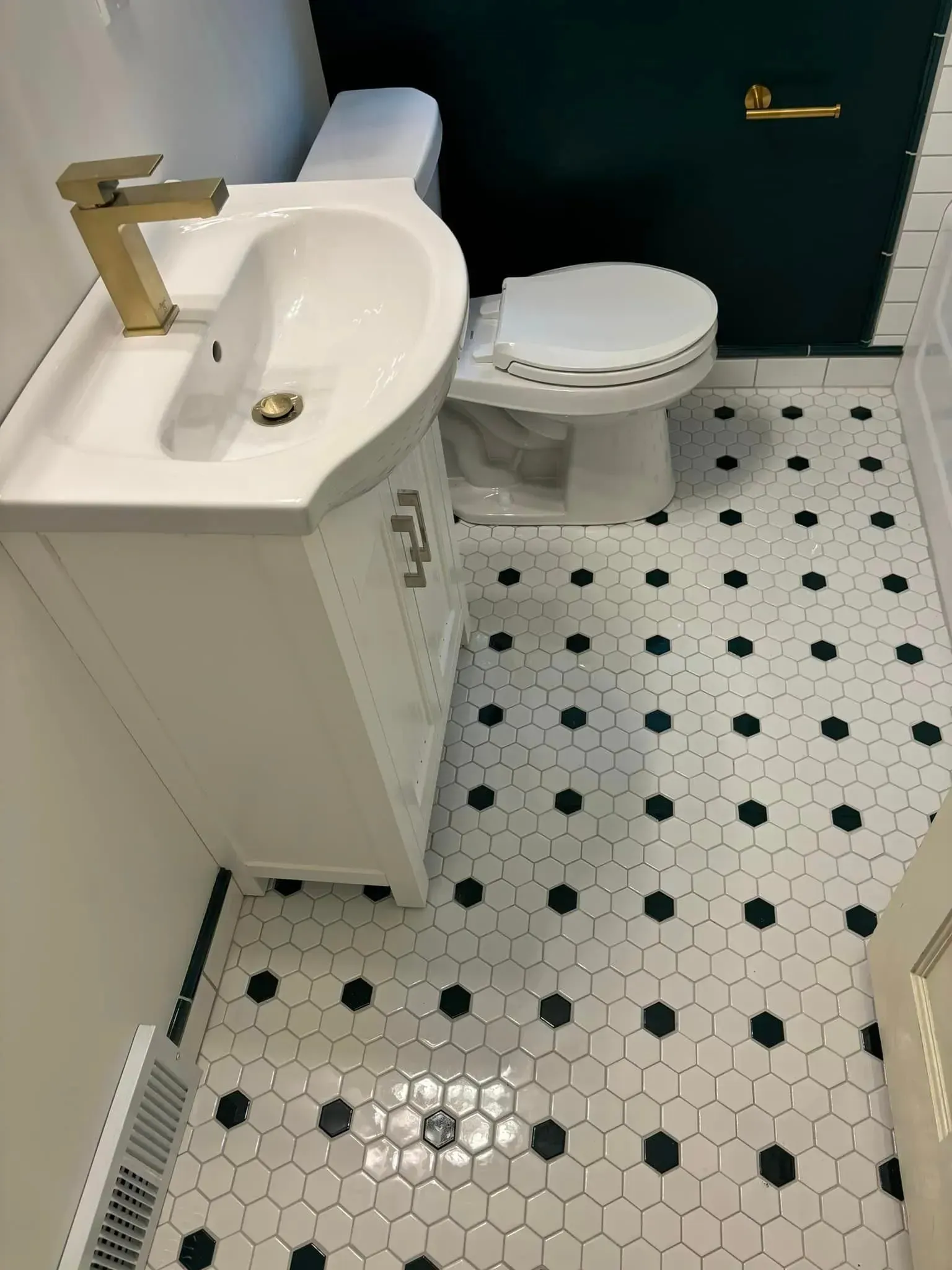 A bathroom with a sink , toilet , and black and white tile floor.