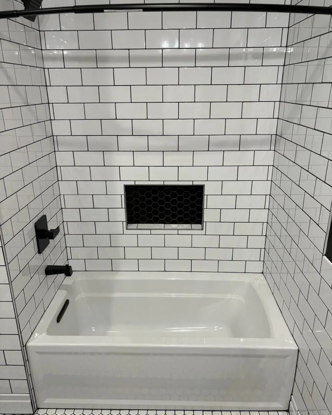 A bathtub in a bathroom with white brick walls