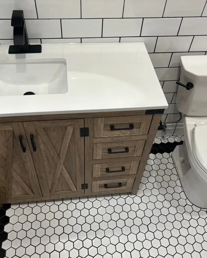 A bathroom with a sink , toilet , and black and white tiles.