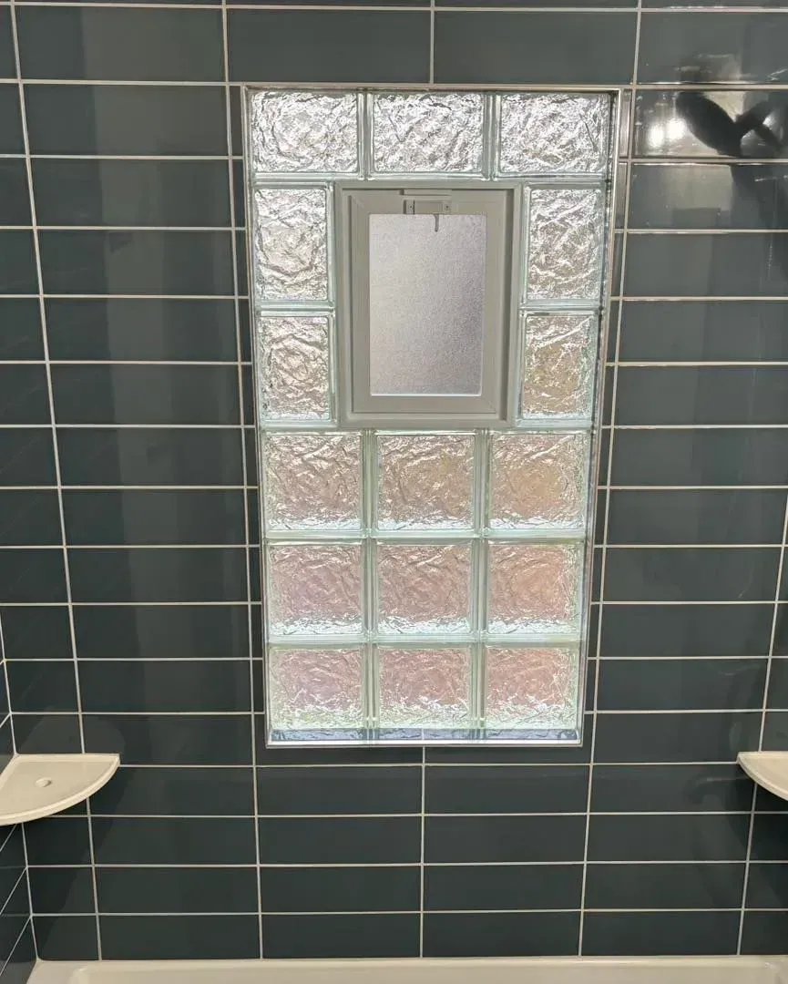A bathroom with a glass block window and a shower head.