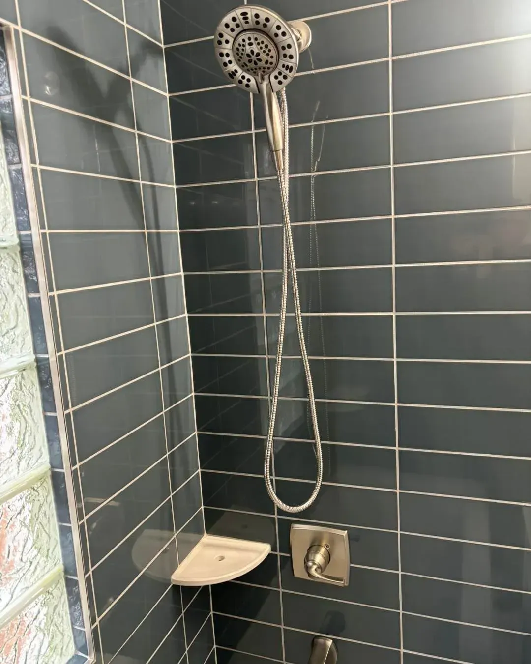 There is a shower head in the corner of the shower.