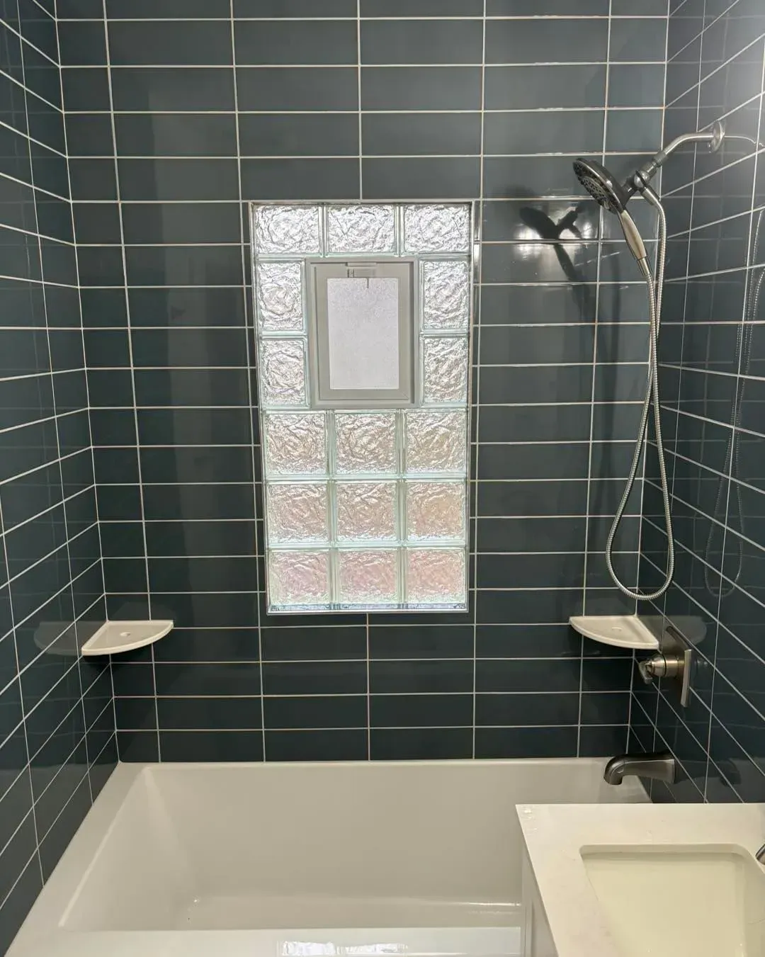 A bathroom with a tub , sink , shower and window.