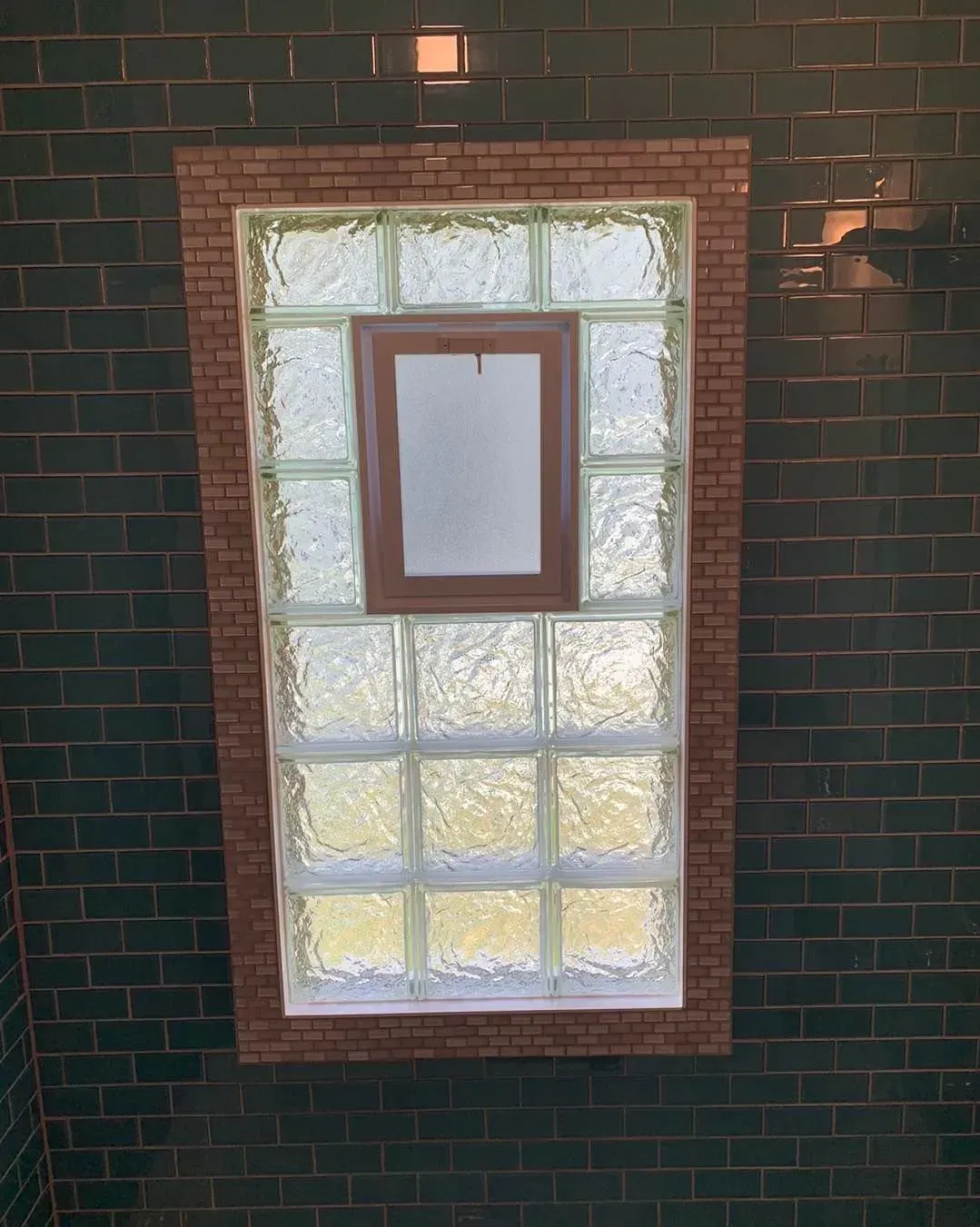 A brick wall with a window made of glass blocks